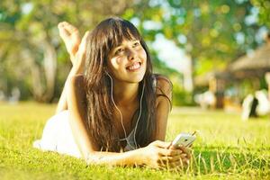 a woman laying on the grass with headphones photo
