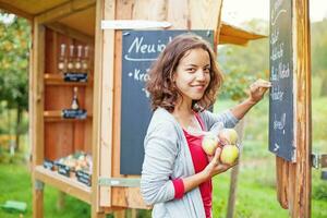 a woman holding an apple and standing next to a chalkboard photo