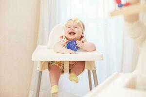 un bebé en un alto silla riendo foto