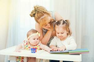 a woman and two children are reading a book photo