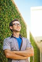 a man with glasses and a tie standing in front of a wall photo