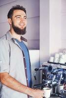 un hombre con un barba en pie en frente de un café máquina foto