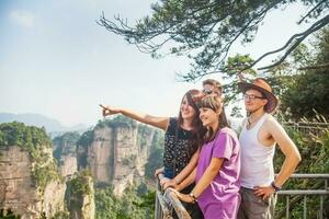 four people standing on a railing overlooking the mountains photo