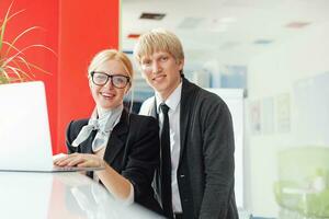 a man and woman standing in front of a laptop photo