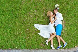 top view of a newlywed couple lying on the grass photo