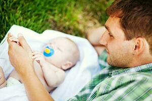 a man laying on the grass with a baby photo