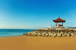 a small pagoda sits on the beach next to the ocean photo