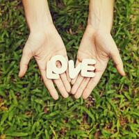 woman holding love word in her hands on grass background photo