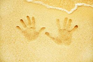 two hands are shown in the sand on a beach photo