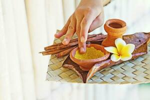 a person holding a bowl of yellow powder and a flower photo