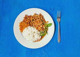 thai food on a white plate with rice and green vegetables photo