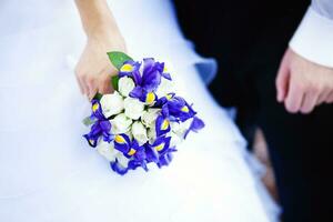 a close up of a bride and groom holding a bouquet of blue and white flowers photo