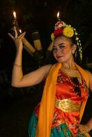 un tradicional asiático bailarín poses en frente de un ardiente antorcha en un naranja disfraz cuales es muy hermosa foto