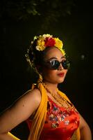 a traditional Javanese dancer stands and dances with a flexible body while wearing sunglasses photo