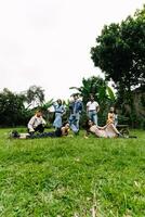 a group of asian people having a picnic in a park with green grass photo