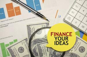 FINANCE YOUR IDEAS words on yellow sticker with dollars with calculator and pen photo