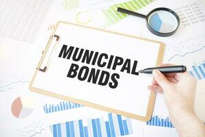 Text MUNICIPAL BONDS on white paper sheet and marker on businessman hand on the diagram. Business concept photo