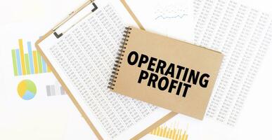 Text OPERATING PROFIT on brown paper notepad on the table with diagram. Business concept photo