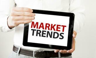 Text MARKET TRENDS on tablet display in businessman hands on the white background. Business concept photo