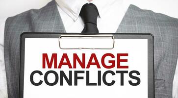 Businessman holding sheet of paper with a message MANAGE CONFLICTS photo