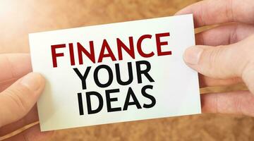 FINANCE YOUR IDEAS word inscription on white card paper sheet in hands of a businessman. photo