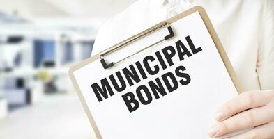 Text MUNICIPAL BONDS on white paper plate in businessman hands in office. Business concept photo