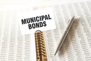 Text MUNICIPAL BONDS on paper card, pen, financial documentation on table photo