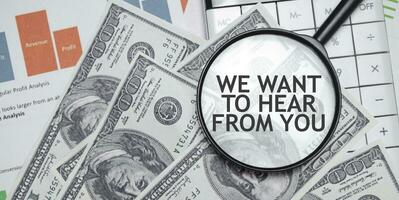 WE WANT TO HEAR FROM YOU words on magnifier glass with dollars and charts photo