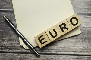 euro Word Written In Wooden Cubes on notebook with pen photo