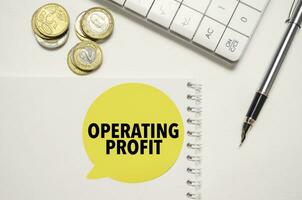 OPERATING PROFIT words on yellow sticker with dollars with calculator and pen photo