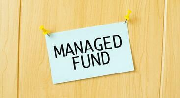 MANAGED FUND sign written on sticky note pinned on wooden wall photo