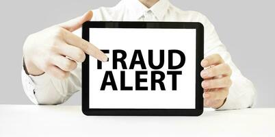 Text fraud alert on tablet display in businessman hands on the white background. Business concept photo