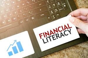 Calculator, red notepad, three colour pencils, silver pen and brown notebook with text FINANCIAL LITERACY photo