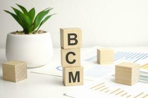 text BCM on wooden dice standing on top of each other photo