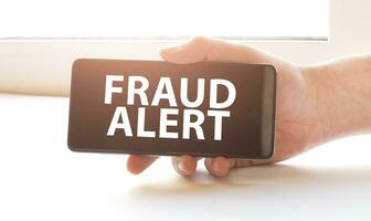 fraud alert on display in hands on white background photo