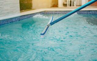 Swimming pool cleaning with brush. Pool brush for wall cleaning, Worker cleaning a pool with special brush photo