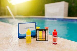 Chlorine test kit on the edge of the pool. PH tester for pool maintenance. Water test kit for swimming pools, Chlorine and ph tester for swimming pools photo