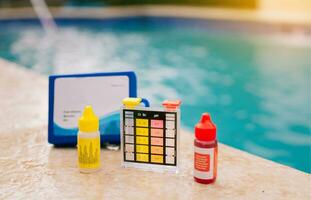 cloro y ph ensayador para nadando quinielas, cloro prueba equipo en el borde de el piscina. ph ensayador para piscina mantenimiento. agua prueba equipo para nadando quinielas foto