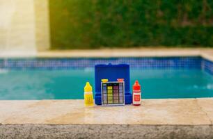 Water test kit for swimming pools. Chlorine and ph tester for swimming pools, Chlorine test kit on the edge of the pool. PH tester for pool maintenance. photo