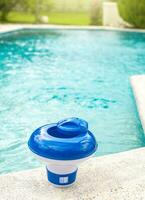 A chlorine float on the edge of a swimming pool. A chlorine dispenser for swimming pools with blue water in the background. Dosing float for swimming pool chlorination photo