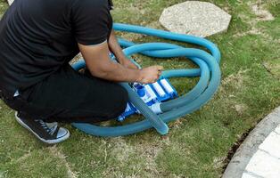 hombre conectando el encargarse de en el piscina vacío. succión equipo conexión para nadando piscina, piscina succión manguera instalación. persona conectando piscina manguera encargarse de foto