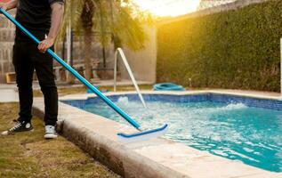 manos de trabajador limpieza un nadando piscina con especial cepillar, mantenimiento persona limpieza nadando piscina con escoba. nadando piscina limpieza con cepillo foto