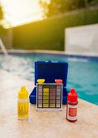 Chlorine test kit on the edge of the swimming pool Mini tester for pool maintenance. Water test kit for swimming pools, Chlorine and ph tester for swimming pools photo