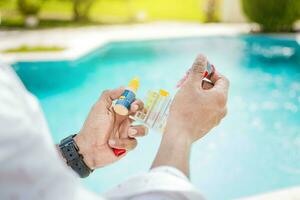 Hand holding a pool ph and chlorine tester, Hand holding Water Test Kit on blurred pool background, Person holding complete water test kit with blurred pool background photo