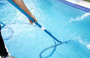 piscina mantenimiento y limpieza con vacío manguera. personas limpieza nadando piscina con succión manguera. de cerca de hombre limpieza un nadando piscina con un vacío manguera foto