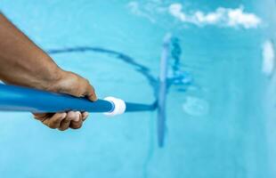 People cleaning swimming pool with suction hose. Close-up of man cleaning a swimming pool with a vacuum hose, Pool maintenance and cleaning with vacuum hose photo