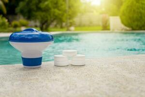 tabletas con cloro dispensador para nadando quinielas. cloro tabletas con dosificación flotar, piscina flotador y cloro tabletas, un piscina flotador y cloro tabletas en el borde de un nadando piscina. foto