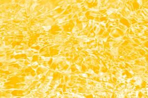 dorado agua con ondas en el superficie. desenfocar borroso transparente oro de colores claro calma agua superficie textura con salpicaduras y burbujas agua olas con brillante modelo textura antecedentes. foto