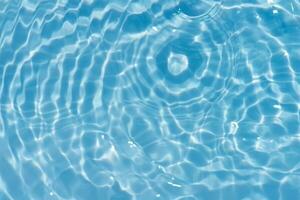 Blue water with ripples on the surface. Defocus blurred transparent blue colored clear calm water surface texture with splashes and bubbles. Water waves with shining pattern texture background. photo