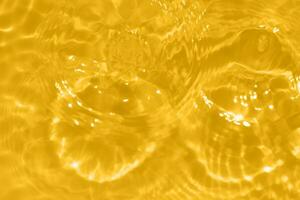 dorado agua con ondas en el superficie. desenfocar borroso transparente oro de colores claro calma agua superficie textura con salpicaduras y burbujas agua olas con brillante modelo textura antecedentes. foto